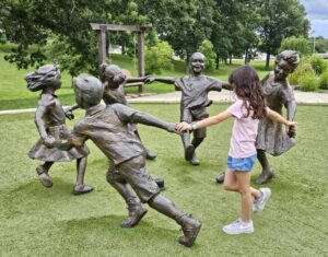 girl playing in park with sculptures of children