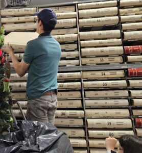 man lifting heavy deed books in county clerk's office. Photo by Rita Oakes.
