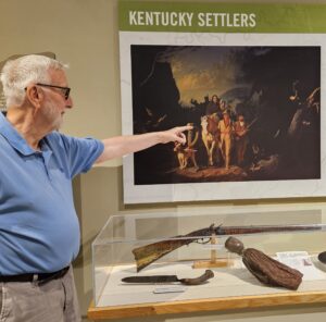 Man pointing to painting of pioneers.