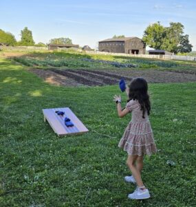 Girl throws a beanbag in Cornhole game.