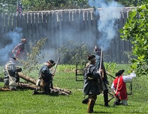 In a reenactment of a battle, indigineous men looks for an entry point into a Kentucky fort.